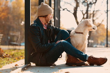 Handsome young hipster with dog outdoors