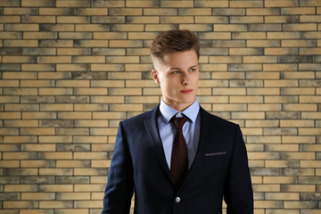 Handsome man in formal suit against brick wall