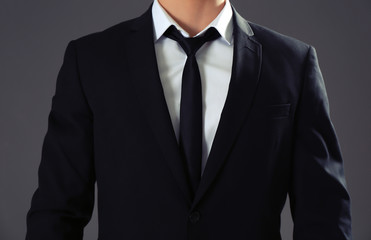 Handsome man in formal suit on grey background, closeup