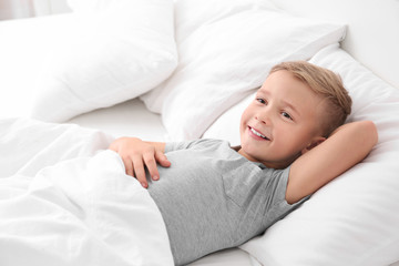Cute boy lying on white pillow at home