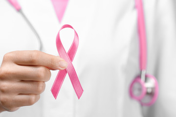 Doctor holding pink ribbon, closeup. Breast cancer awareness concept