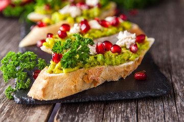 Toast with avocado and pomegranate on wooden table