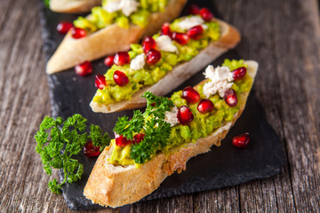 Toast with avocado and pomegranate on wooden table