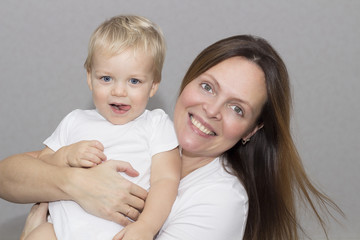 happy young mother with a child on light grey background