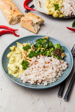 Handmade chicken curry tikka masala with basmati rice and broccoli on grey table