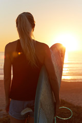 Beach sunset sexy surfer woman surfing lifestyle relaxing holding surfboard looking at ocean waves