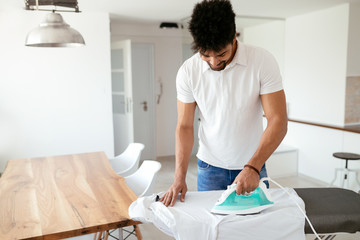Man ironing shirt on ironing board