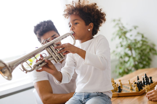 Girl with her father learning trumpet
