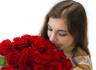 Brown hair woman is holding a bouquet of beautiful red roses and smelling them close up