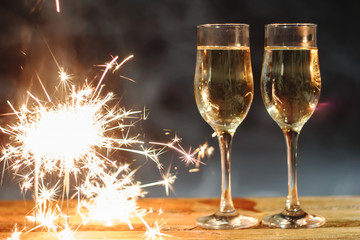 Two glasses of champagne and sparklers candles on the table
