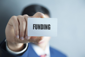 FUNDING word on business card shown by a man
