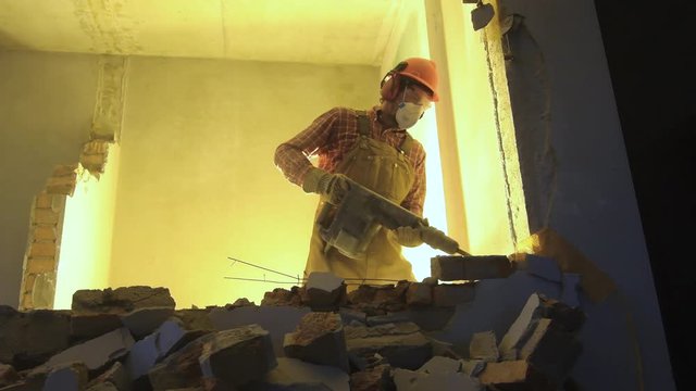 worker with demolition hammer breaking interior wall
