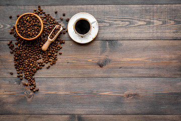 Coffee concept. Roasted beans and cup of espresso on dark wooden background top view copyspace