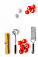Fototapeta na wymiar Cooking italian pasta. Spaghetti, tomatoes, garlic and cookware on white background top view copyspace