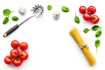 Cooking italian pasta. Spaghetti, tomatoes, garlic, basil and cookware on white background top view copyspace