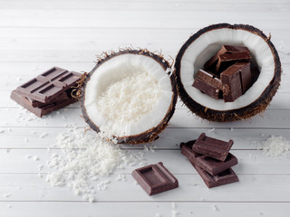 Fresh organic coconut broken into two parts with chocolate on a rustic wooden background