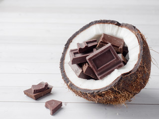 Fresh organic coconut broken into two parts with chocolate on a rustic wooden background