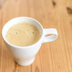 Weiße Kaffeetasse mit Kaffee auf einem Holztisch