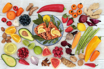Healthy diet food to promote heart health concept with superfoods of salmon, fruit, vegetables, nuts, spice and herbs providing high levels of omega 3 fatty acids, anthocyanins and antioxidants.