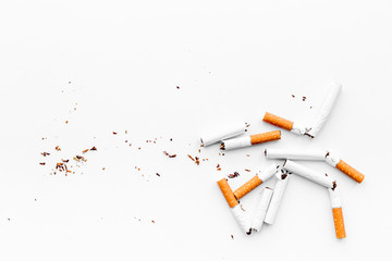 Smoking. Half-smoked cigarettes with ash on white background top view copyspace