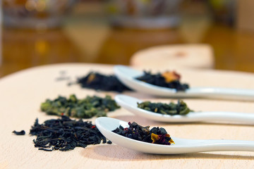 ceramic tea spoon with tea of green tea on white wooden Board