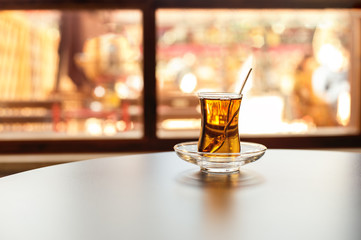 Turkish tea in traditional glass cup indoors on a table close to the window. reflection of the view inside a cup