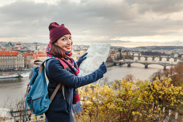 woman tourist traveler looking at the map on the background of famous bridges over Vltava