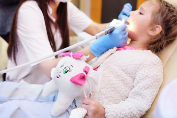 The dentist examines a child's teeth in a dental chair.