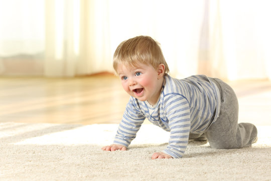 Happy baby crawling and laughing on a carpet