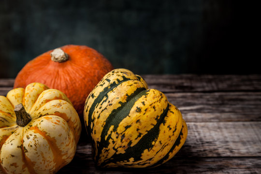 Three colourful various squash on wooden table with dark background