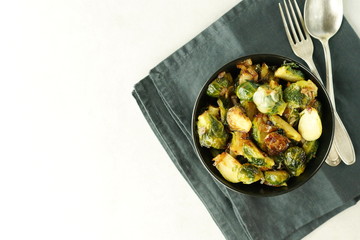 Homemade Roasted Brussel Sprouts with salt, pepper and onions in black bowl on grey background. Top view. Copy spce