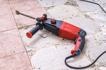 Removing old tiles. Jackhammer - drilling demolition hammer on floor.