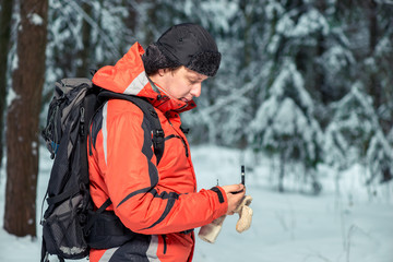 Fototapeta na wymiar tourist with a compass and a backpack got lost in the winter forest