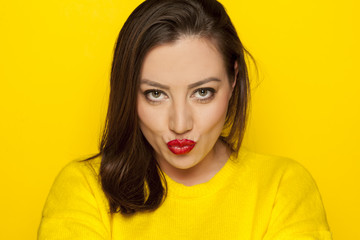 Fototapeta premium beautiful sexy woman in a yellow blouse with kissing gesture on a yellow background