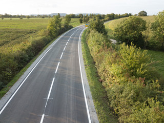 Empty road between green bushes in the summer