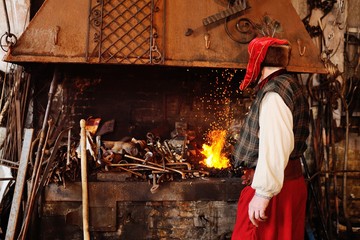 a blacksmith with a beautiful mustache in the smithy burns out a metal product in the furnace.