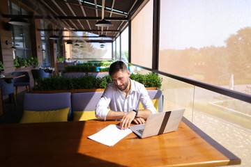 Copywriter typing text on laptop at cafe table.
