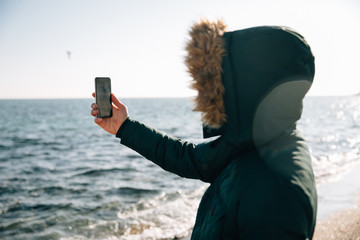 Guy taking a selfie on smartphone by the sea