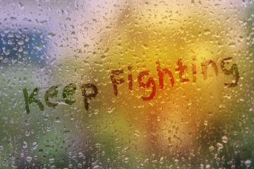 draw text Keep Fighting on natural water drops glass window background