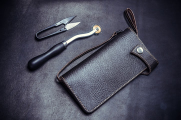 Black leather wallet and tools on black background