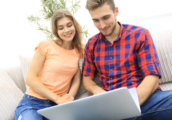 Happy modern couple surfing the net and working on laptop at home