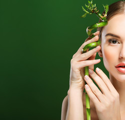 young beautiful woman with bamboo over green background