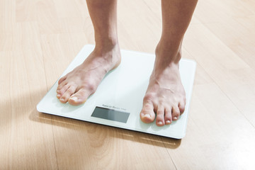 Healthy diet, fitness and weight loss concept. The legs of a young woman on the scales. Checking the weight.