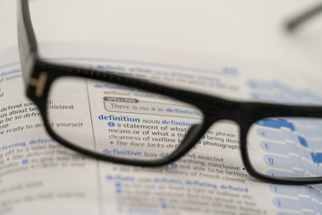 Dictionary showing the word definition  through a pair of reading glasses