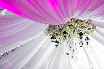 Chandelier made of roses and white flowers hangs under the light tent. decorative lights