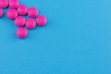 pink round pills on blue background with copy space