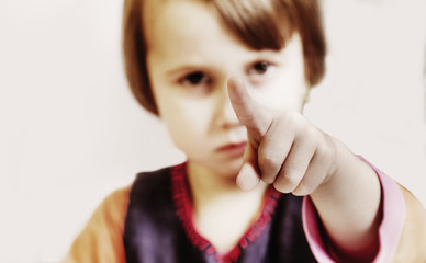 Portrait of a serious little child girl pointing at you as if he wants to say: you must be...
