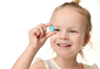 Young baby girl hold light blue headache  pill medicine tablet in small hand 