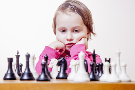 Young beautiful caucasian child girl playing a game of chess. (Development, learning, childhood, wunderkind concept)