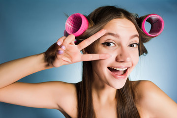 happy young girl showing two fingers on head of hair curlers